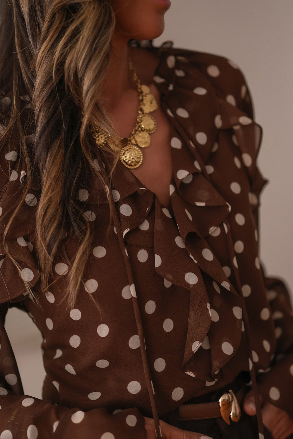 Chemisier à pois café, col V à volants et manches longues cloche, orné de volants.