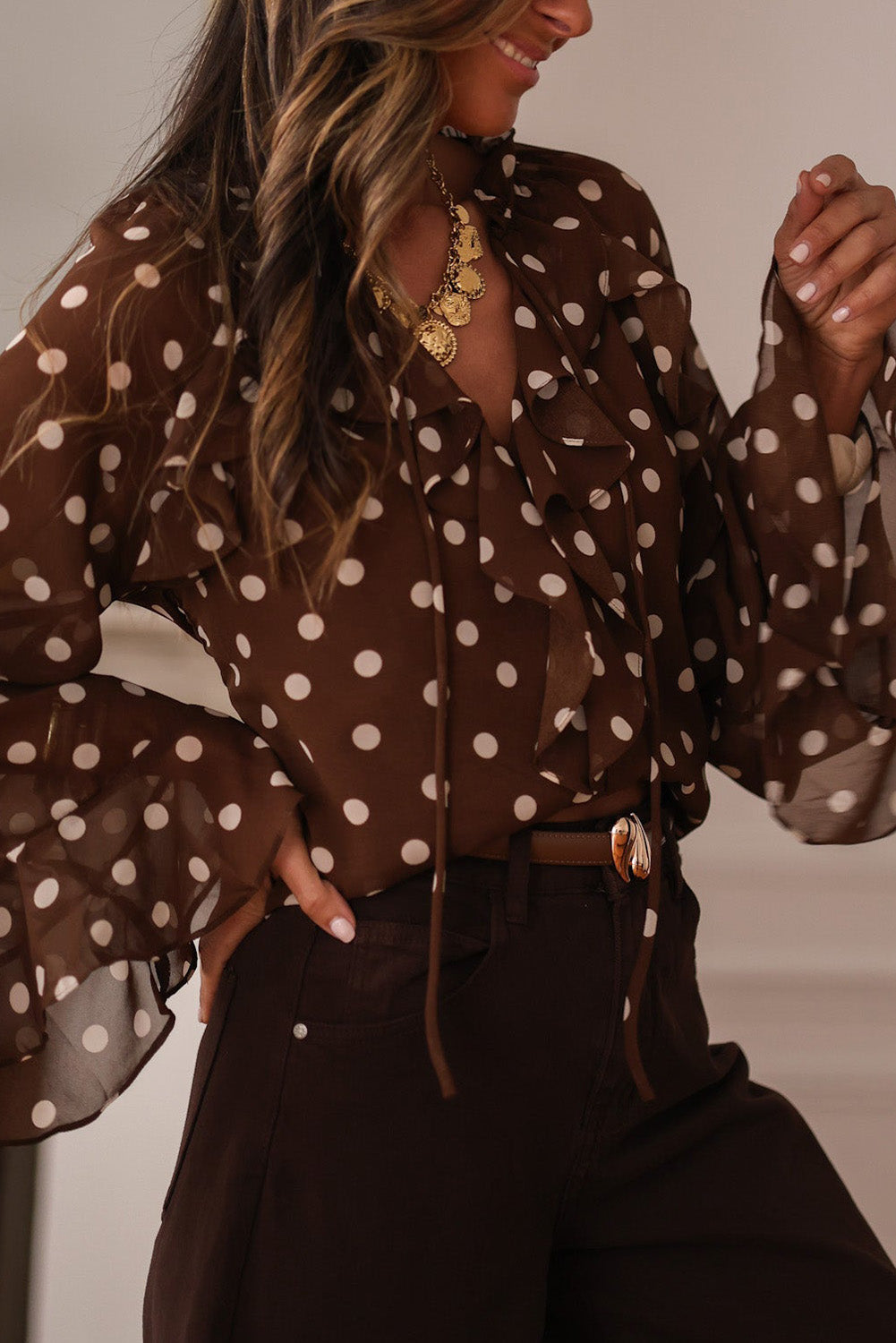 Chemisier à pois café, col V à volants et manches longues cloche, orné de volants.