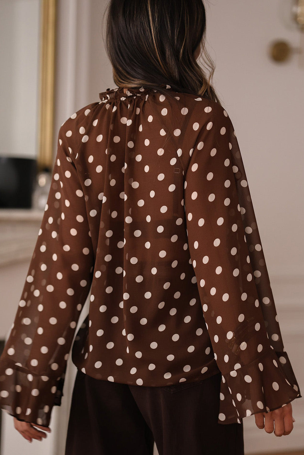 Chemisier à pois café, col V à volants et manches longues cloche, orné de volants.