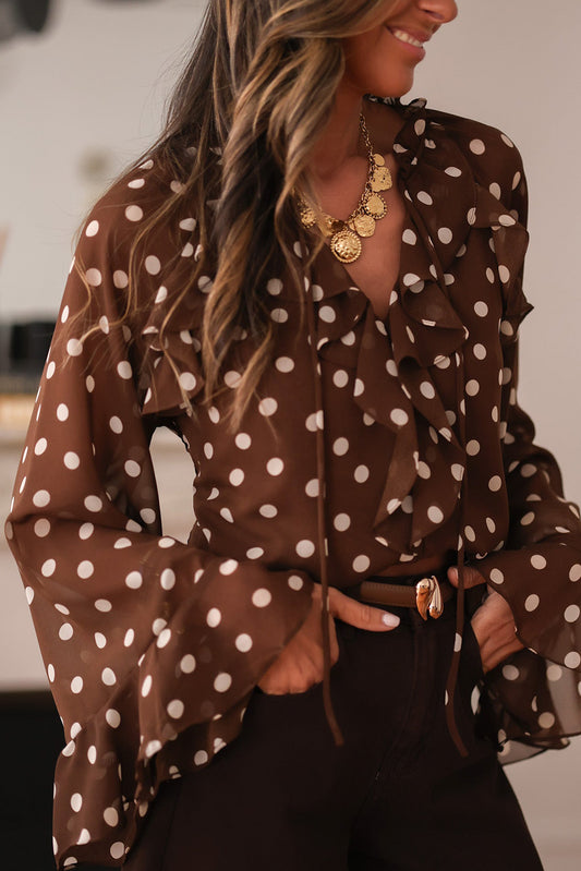 Chemisier à pois café, col V à volants et manches longues cloche, orné de volants.